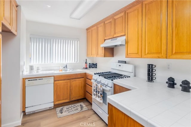 kitchen featuring tile counters, sink, white appliances, and light hardwood / wood-style floors