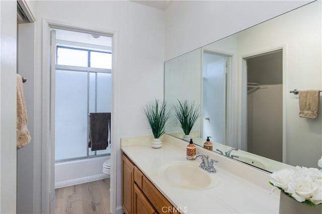 full bathroom with toilet, vanity, wood-type flooring, and combined bath / shower with glass door