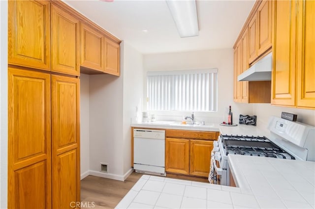 kitchen with tile counters, sink, light hardwood / wood-style flooring, and white appliances