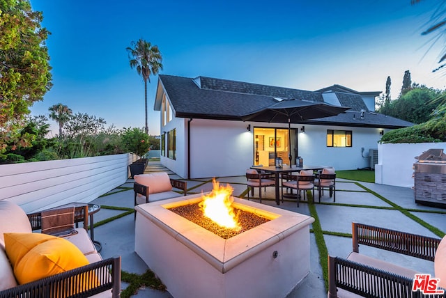 patio terrace at dusk with an outdoor living space with a fire pit