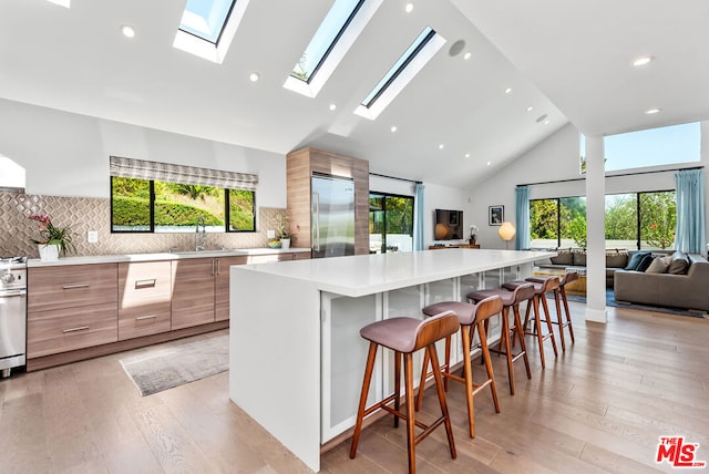 kitchen featuring stainless steel built in fridge, a skylight, a kitchen breakfast bar, and plenty of natural light