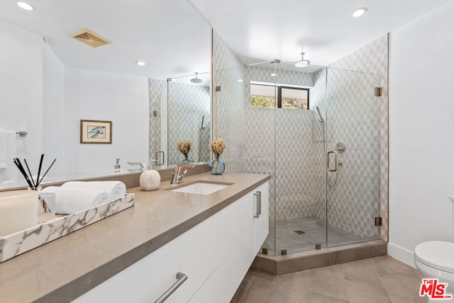 bathroom with vanity, toilet, tile patterned floors, and a shower with shower door