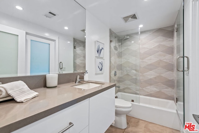 full bathroom featuring shower / bath combination with glass door, vanity, tile patterned flooring, and toilet