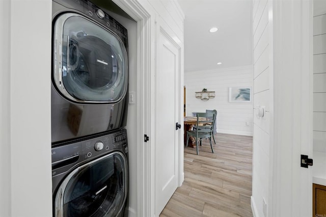 clothes washing area featuring light wood-type flooring and stacked washer / dryer