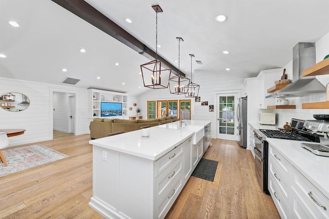 kitchen with white cabinetry, wall chimney exhaust hood, hanging light fixtures, and appliances with stainless steel finishes