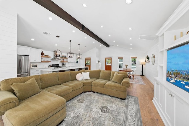 living room with lofted ceiling with beams and light hardwood / wood-style floors