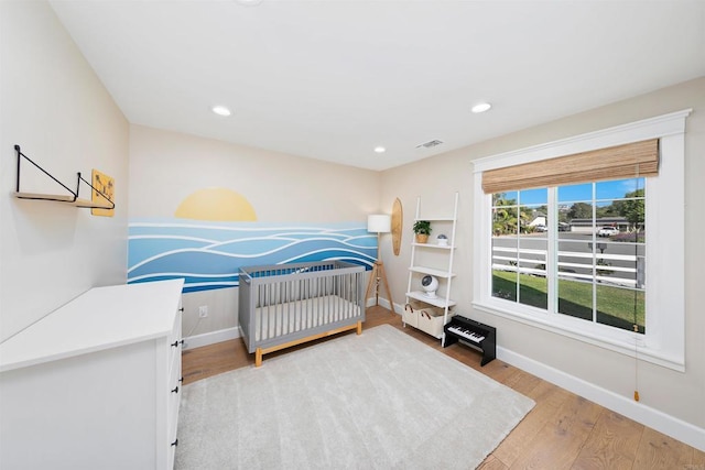 bedroom featuring a crib and wood-type flooring