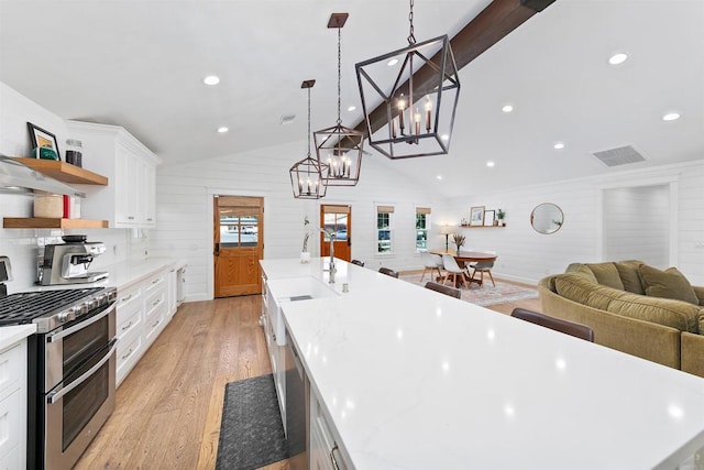 kitchen featuring pendant lighting, range with two ovens, white cabinetry, and vaulted ceiling