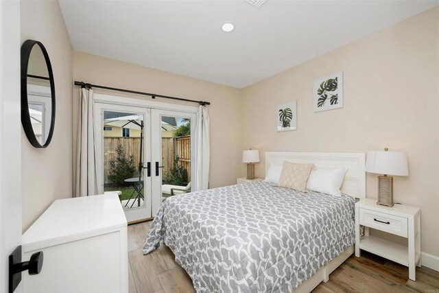 bedroom with access to exterior, hardwood / wood-style floors, and french doors