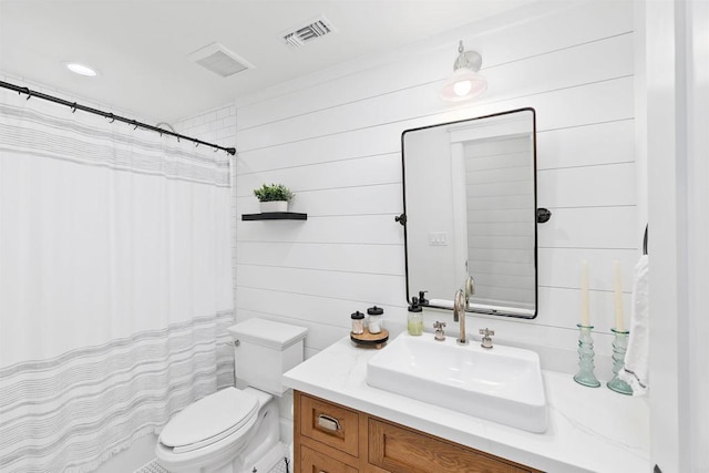 bathroom with vanity, wood walls, toilet, and walk in shower