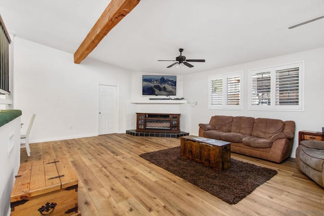 living room featuring a fireplace, light hardwood / wood-style flooring, beamed ceiling, and ceiling fan