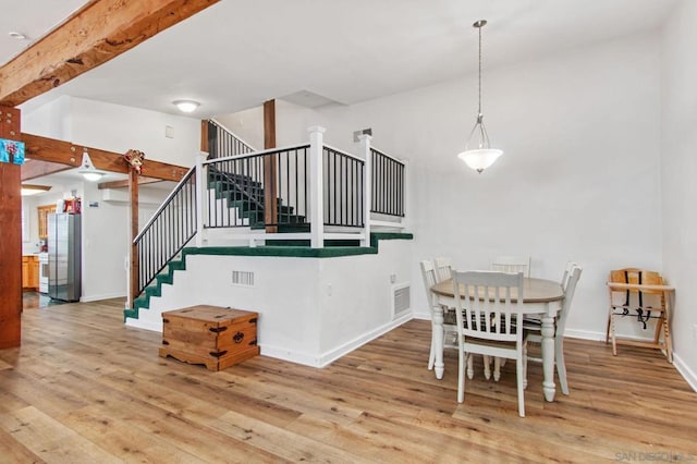 dining area featuring beamed ceiling, high vaulted ceiling, and light wood-type flooring