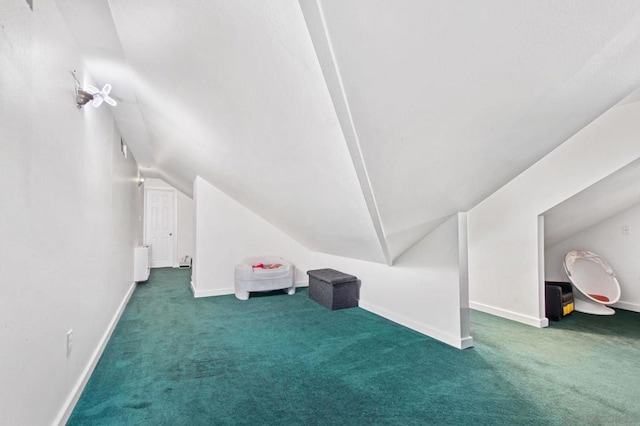 additional living space featuring lofted ceiling, radiator, and dark carpet