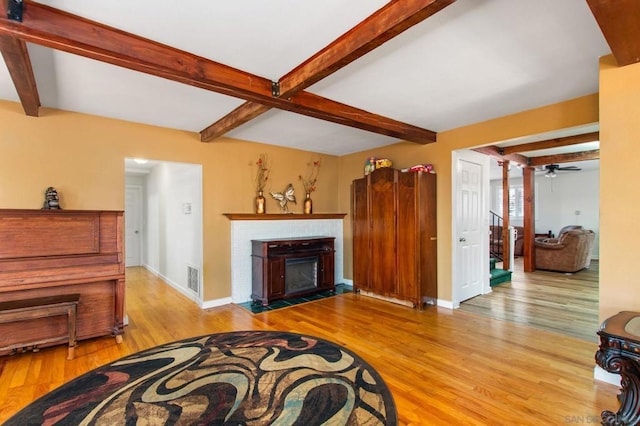 living room featuring beamed ceiling, ceiling fan, and light hardwood / wood-style floors