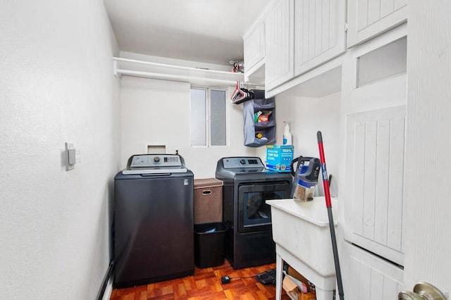 clothes washing area featuring separate washer and dryer, parquet flooring, and cabinets