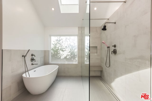 bathroom with plus walk in shower, tile walls, a skylight, and tile patterned floors