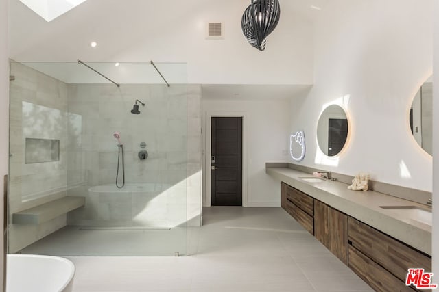 bathroom with a towering ceiling, vanity, tile patterned flooring, and a tile shower