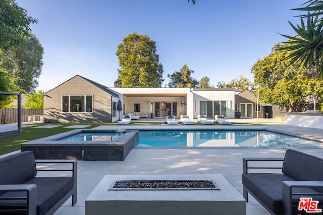 view of pool featuring a patio, an in ground hot tub, and an outdoor living space with a fire pit