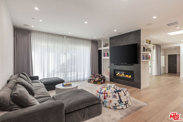 living room with light hardwood / wood-style flooring and a large fireplace