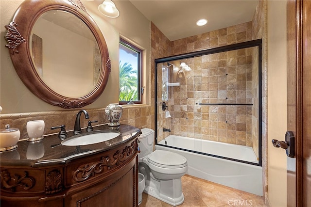 full bathroom featuring vanity, toilet, tile patterned floors, tile walls, and combined bath / shower with glass door