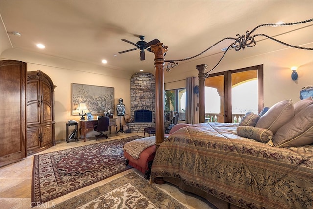 bedroom with ceiling fan, access to exterior, and a stone fireplace