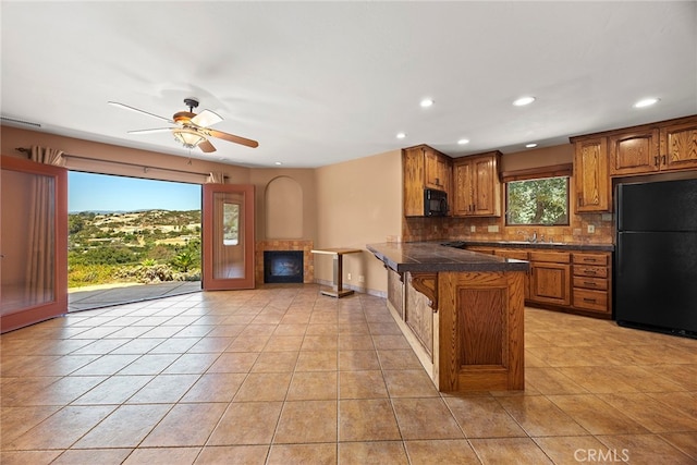 kitchen featuring ceiling fan, sink, kitchen peninsula, black appliances, and decorative backsplash