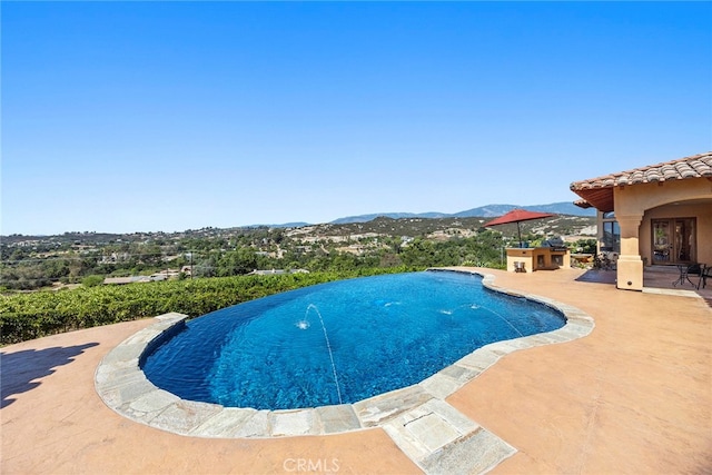 view of pool featuring a mountain view, a patio, and pool water feature