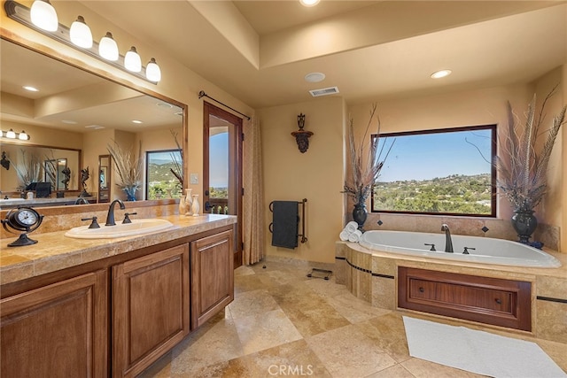 bathroom featuring vanity and a relaxing tiled tub