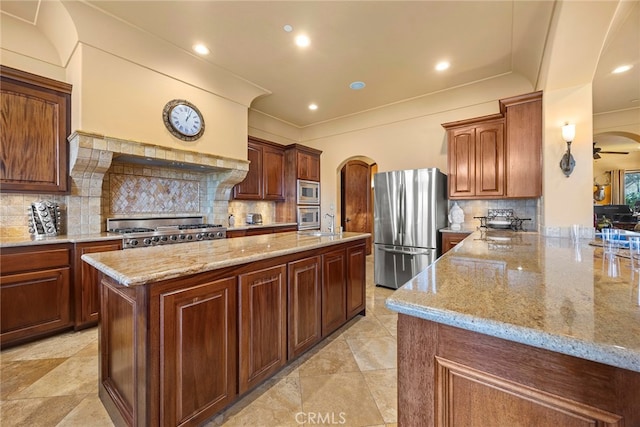 kitchen featuring light stone counters, kitchen peninsula, stainless steel appliances, and tasteful backsplash