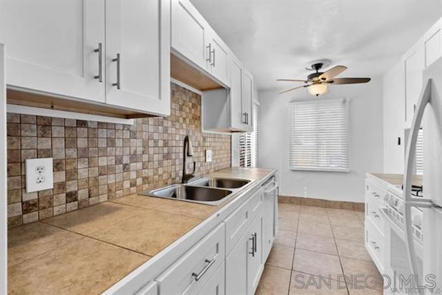 kitchen with white cabinetry, sink, backsplash, tile countertops, and light tile patterned flooring