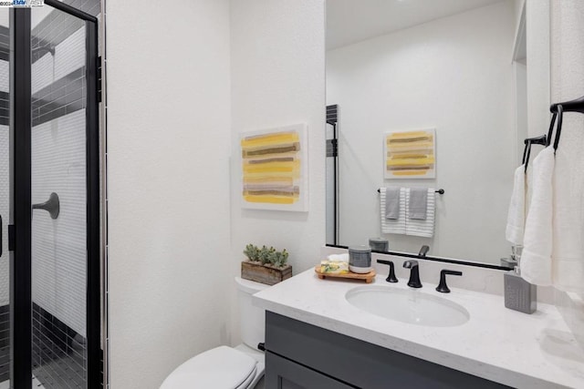 bathroom with a shower with door, vanity, and toilet