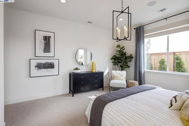 bedroom featuring light colored carpet and a notable chandelier