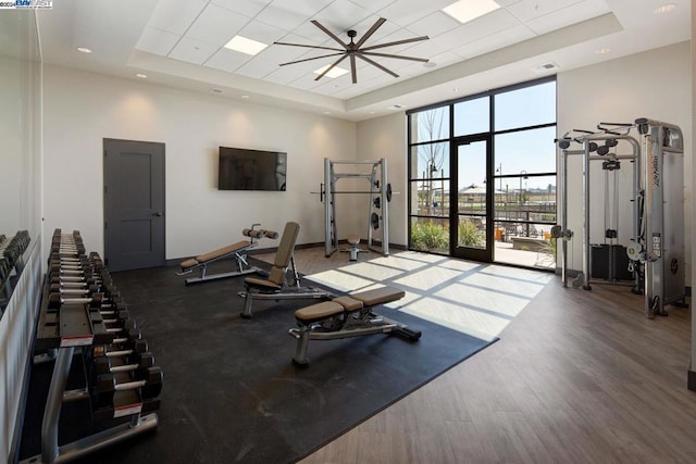 exercise room with a high ceiling, a tray ceiling, and dark hardwood / wood-style floors