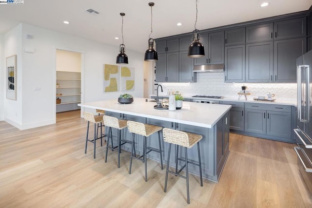 kitchen featuring a breakfast bar area, a center island with sink, pendant lighting, and stainless steel appliances