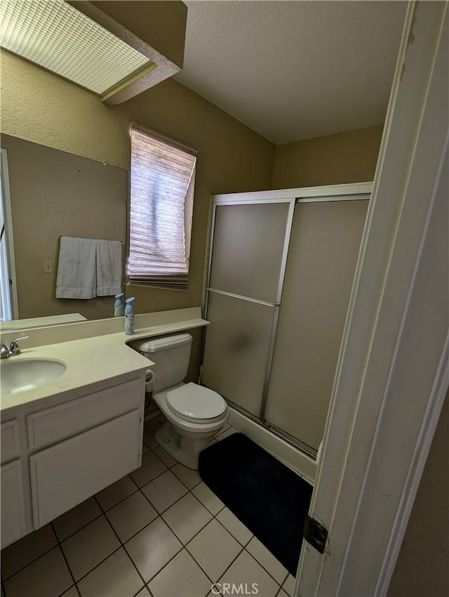 bathroom featuring tile patterned flooring, vanity, toilet, and an enclosed shower