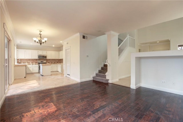 unfurnished living room featuring a chandelier, wood-type flooring, and ornamental molding