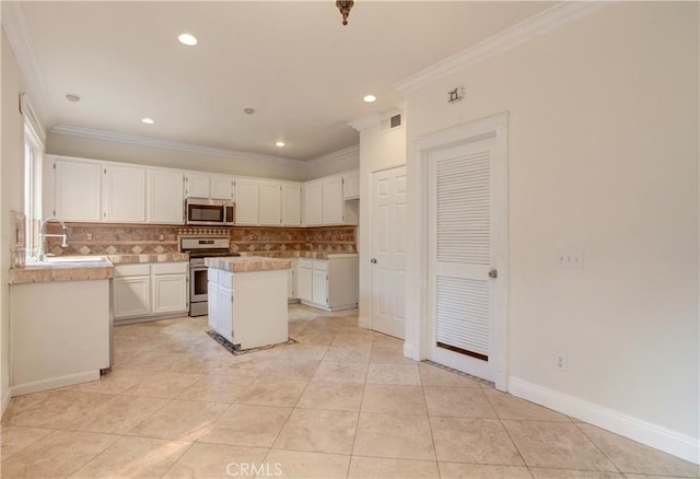 kitchen with tasteful backsplash, stainless steel appliances, crown molding, white cabinetry, and a kitchen island