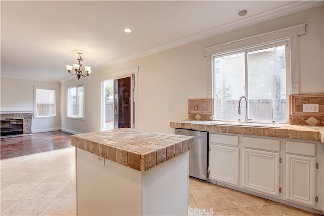 kitchen with stainless steel dishwasher, a kitchen island, sink, white cabinetry, and hanging light fixtures