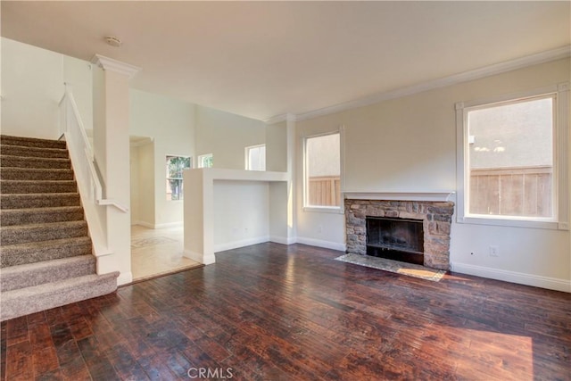 unfurnished living room featuring a stone fireplace, ornamental molding, and dark wood-type flooring