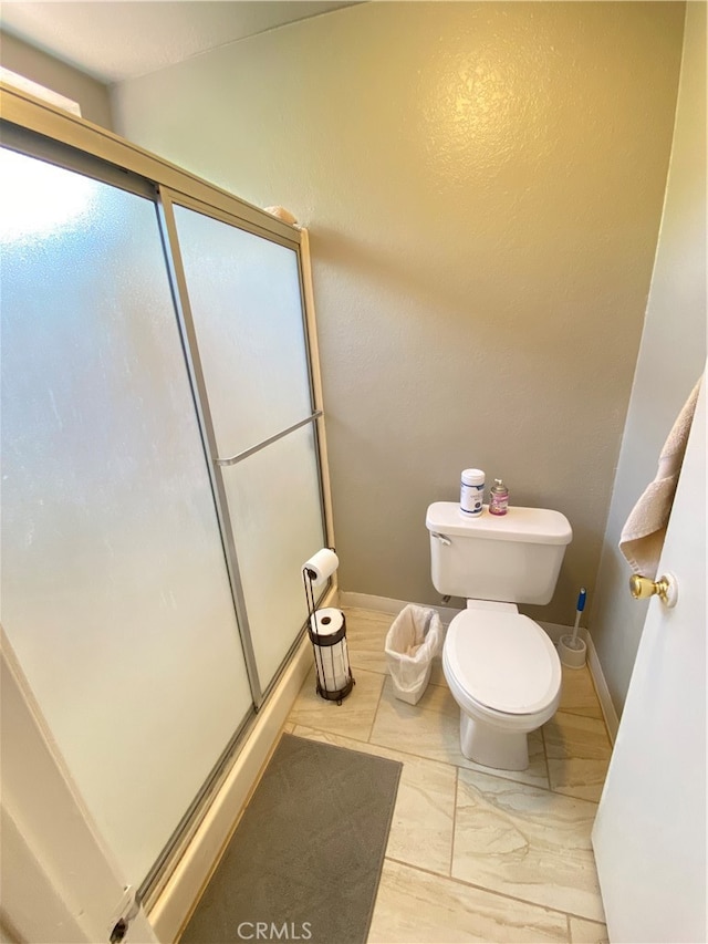 bathroom with a shower with shower door and toilet