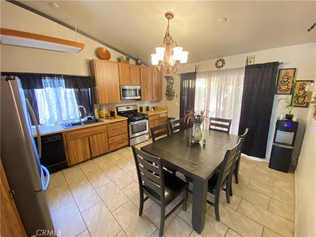 kitchen featuring pendant lighting, lofted ceiling, sink, appliances with stainless steel finishes, and a notable chandelier