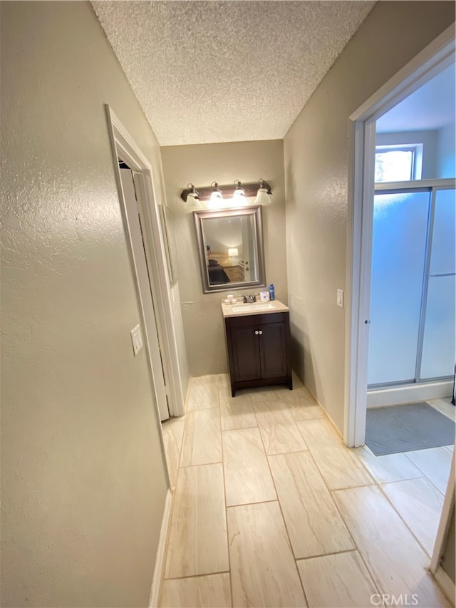 bathroom featuring walk in shower, a textured ceiling, and vanity