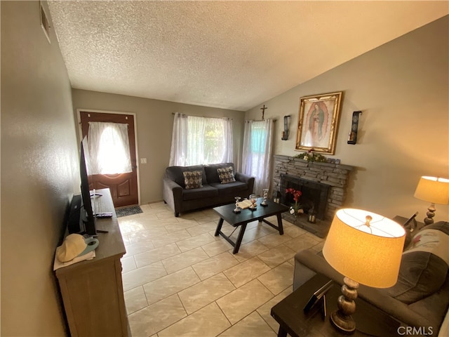 living room with a textured ceiling, a fireplace, vaulted ceiling, and light tile patterned floors