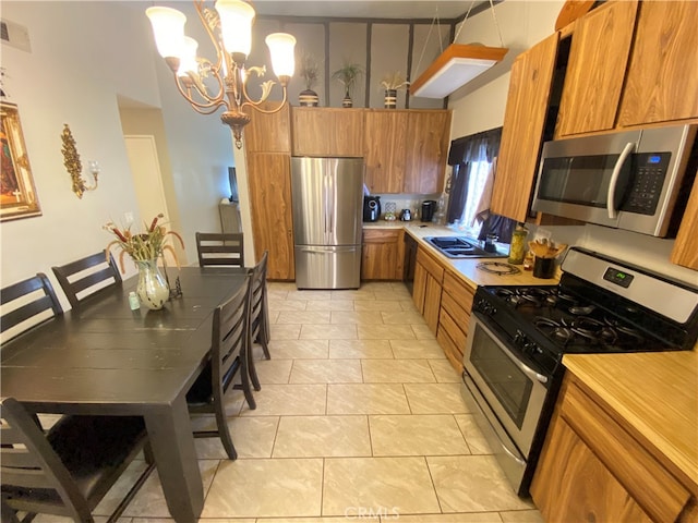 kitchen with appliances with stainless steel finishes, light tile patterned floors, pendant lighting, sink, and a chandelier