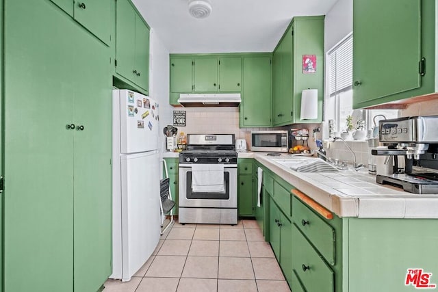 kitchen with light tile patterned floors, green cabinetry, stainless steel appliances, and tile counters