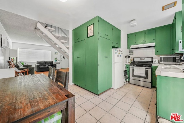 kitchen with green cabinets, stainless steel appliances, tile countertops, and tasteful backsplash