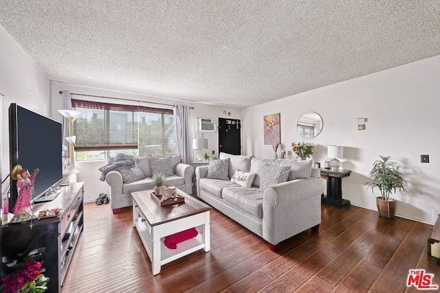 living room with a textured ceiling, dark hardwood / wood-style flooring, and an AC wall unit