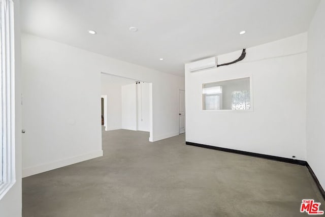 empty room featuring concrete flooring and a wall mounted air conditioner