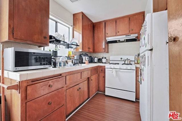 kitchen featuring white appliances, tasteful backsplash, and dark hardwood / wood-style flooring