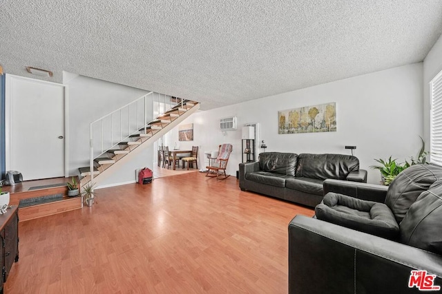 living room with hardwood / wood-style flooring, a textured ceiling, and an AC wall unit